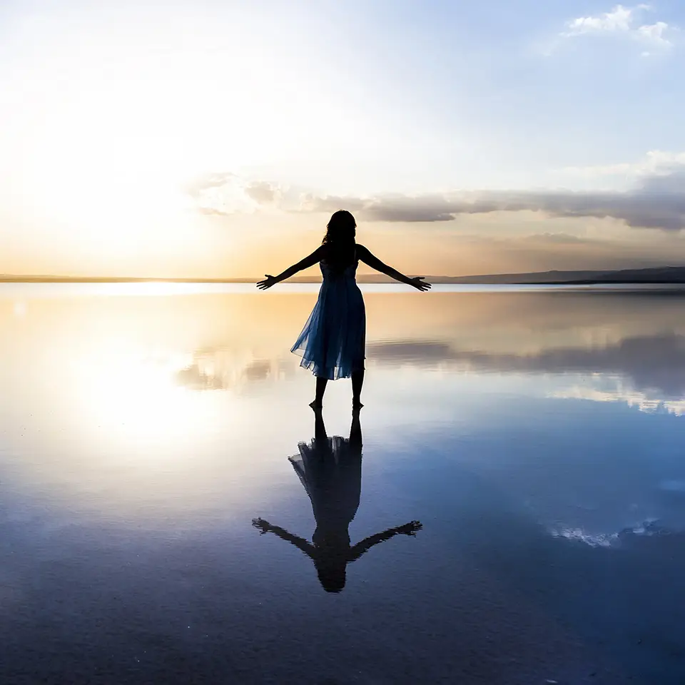A silhouetted woman standing in shallow water
