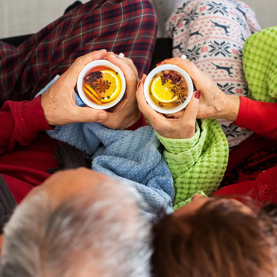 A couple under the blanket, each holding a cup of herbal tea with tea