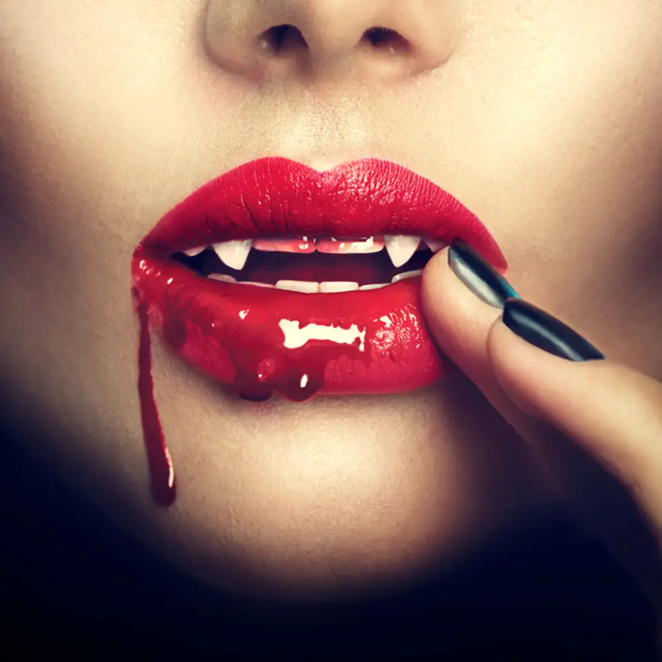 Lips of a female vampire with blood dripping from the corner of her mouth