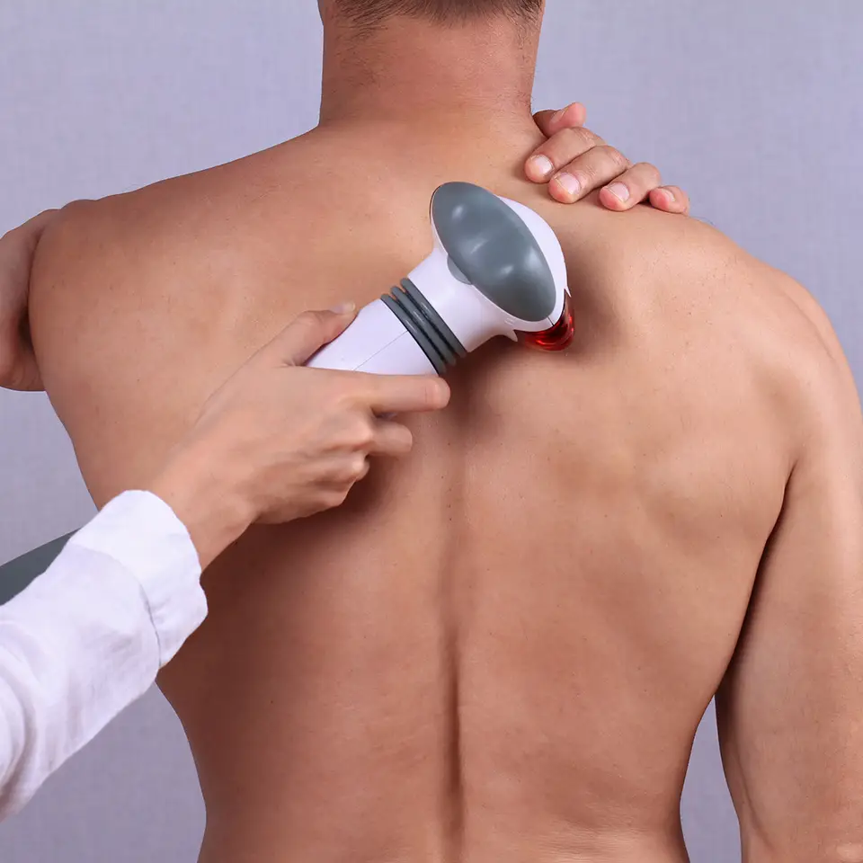 Therapist applying an infrared treatment on a man's back