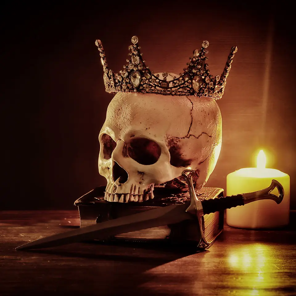 Human skull, old book, sword, crown and burning candle on an old wooden table and dark background