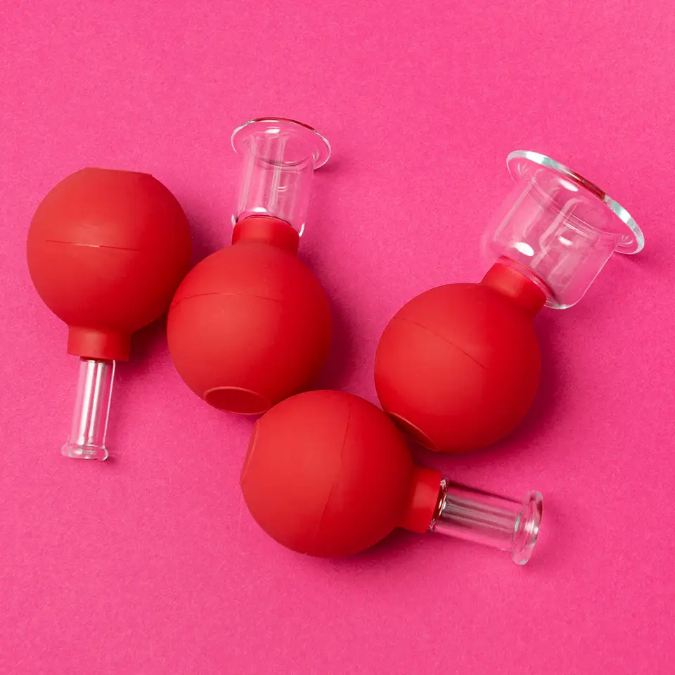 Glass facial and body cupping set on a pink background