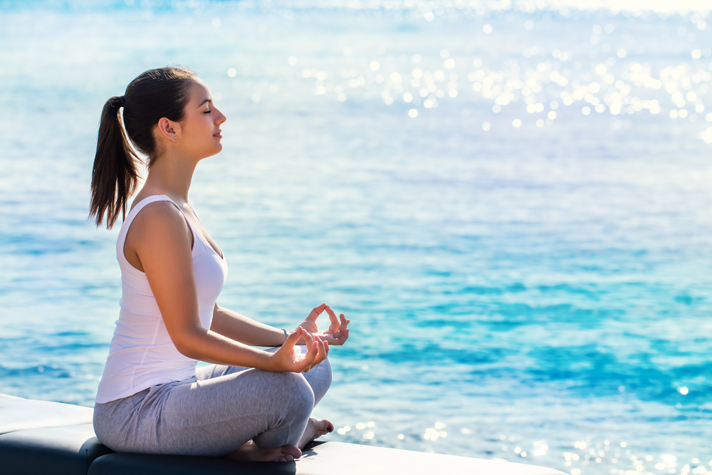 A woman meditating next to the sea