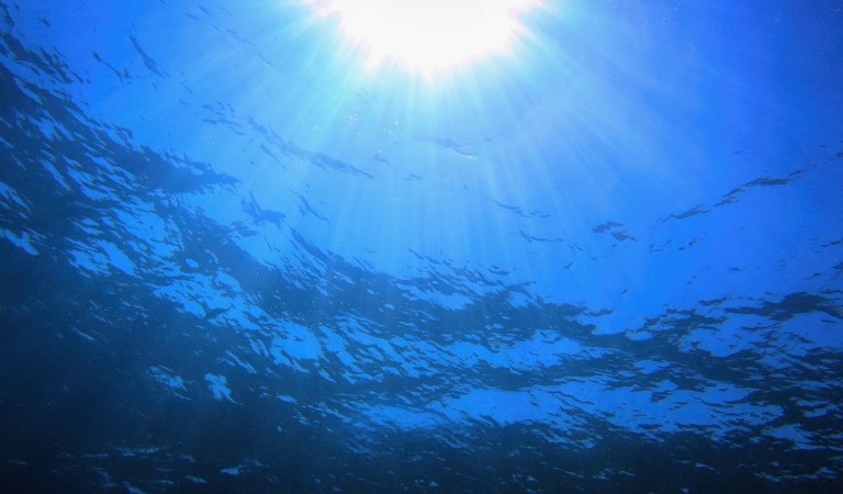 dark sea under water with sun above