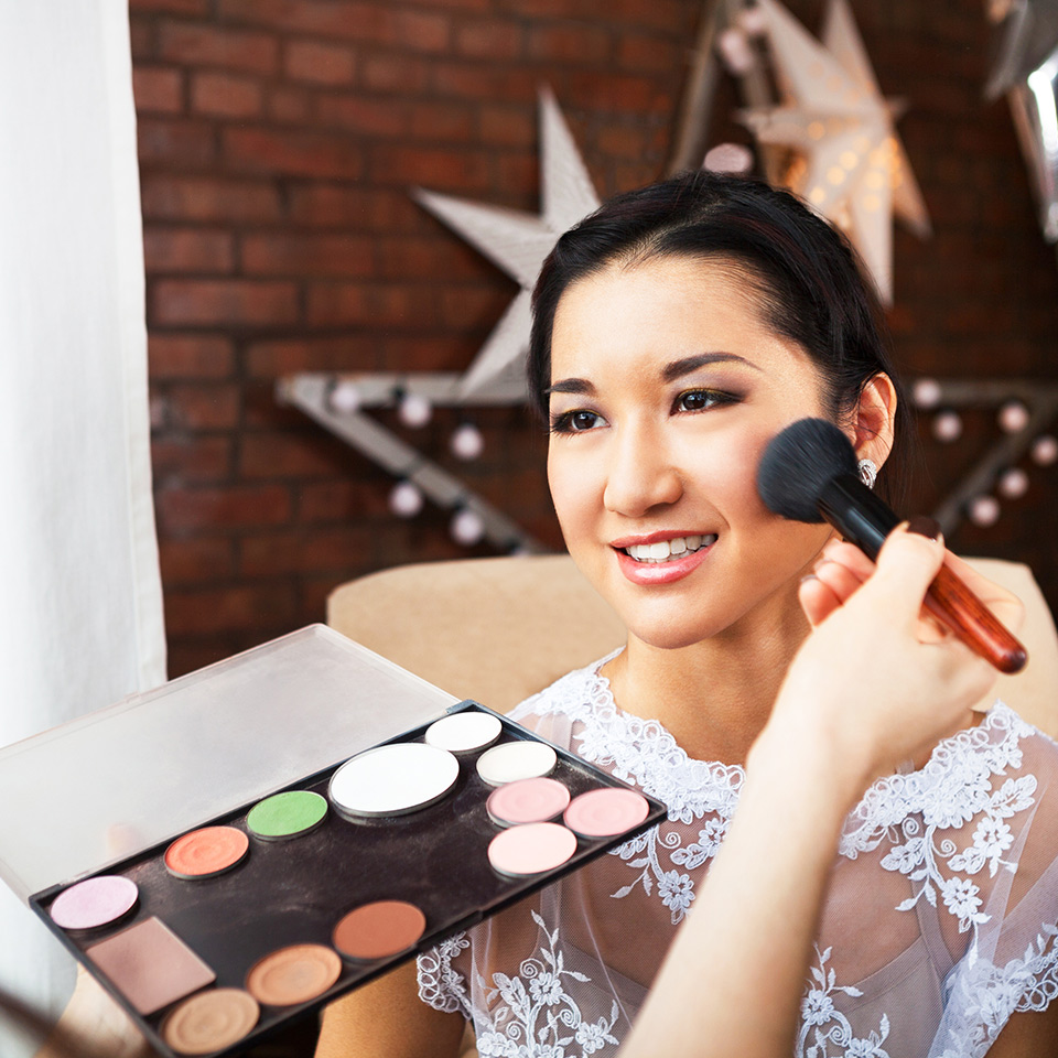 Makeup artist applying wedding makeup to a bride