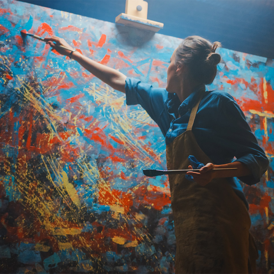 Artist energetically and enthusiastically making sweeping brush strokes on a large canvas after taking an oil painting course