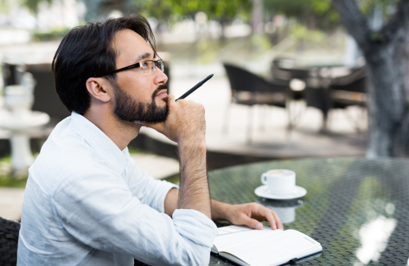 Image of a man thinking and writing.