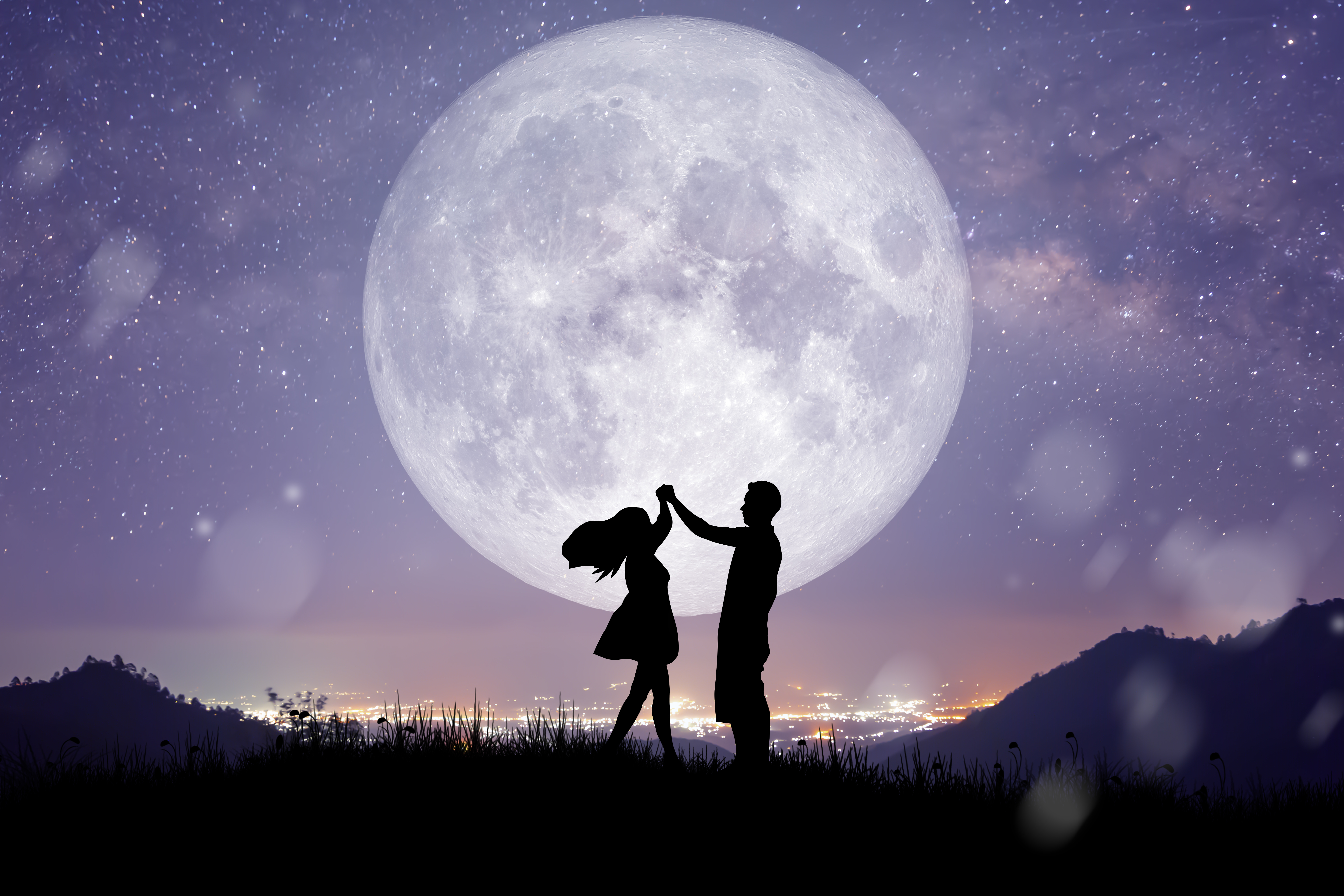 Silhouette of a couple dancing in front of a full moon