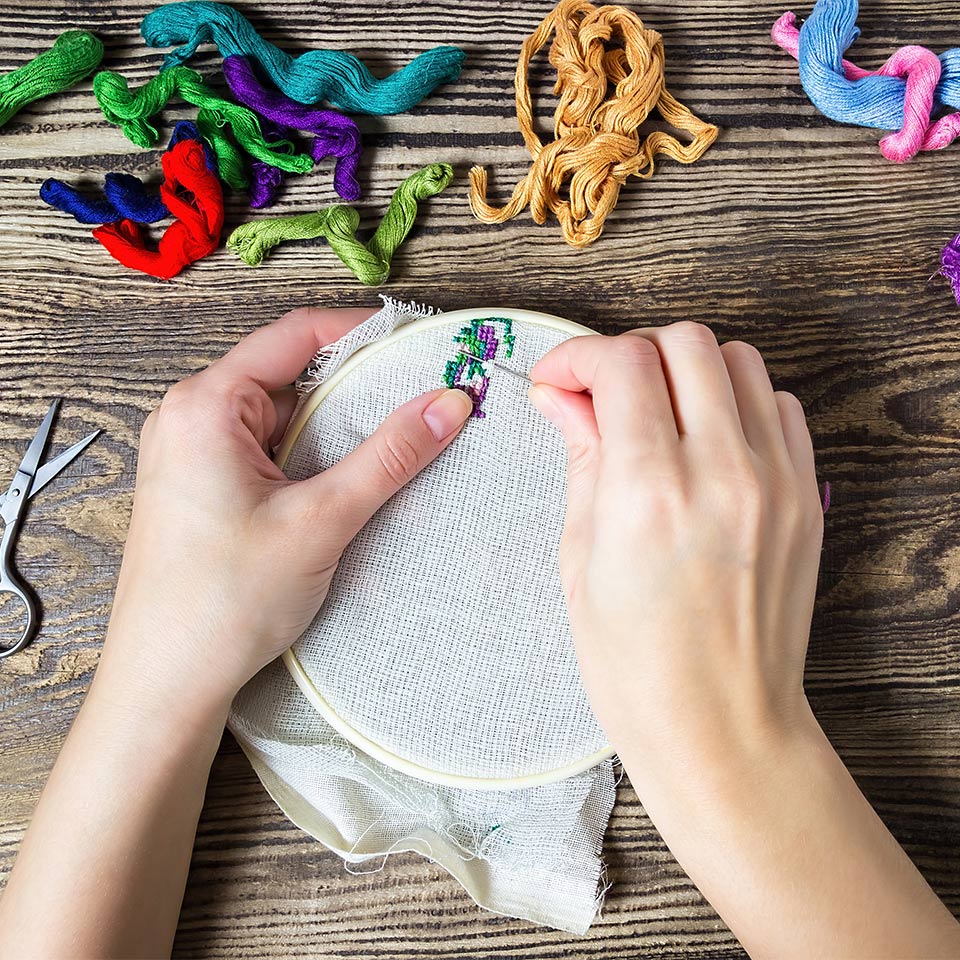A pair of hands doing cross-stitch
