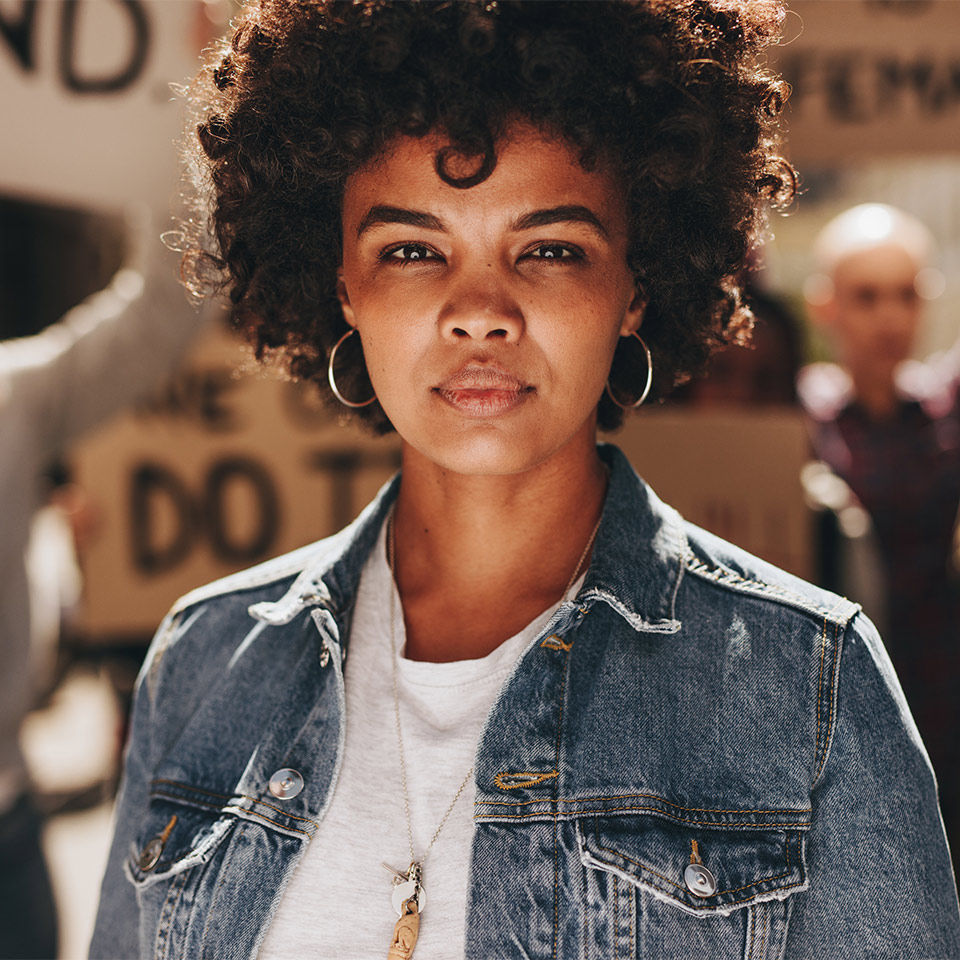 Woman standing outdoors with a group of demonstrators in the background