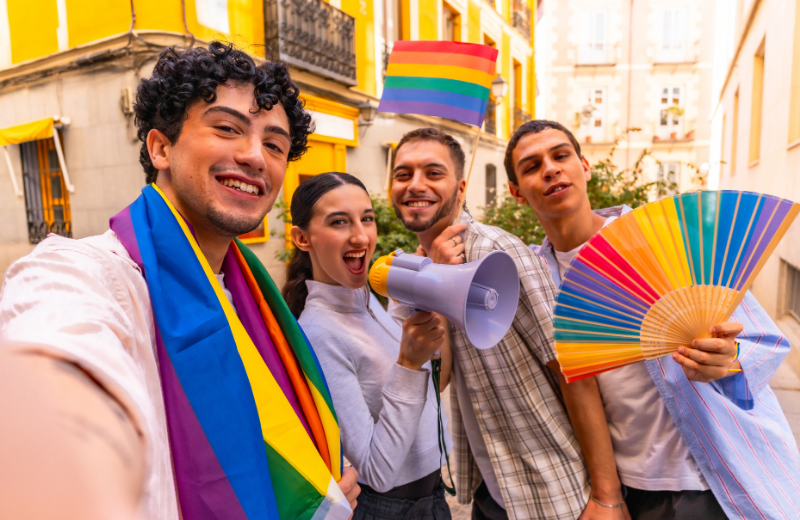people at the Pride parade wearing rainbow flags