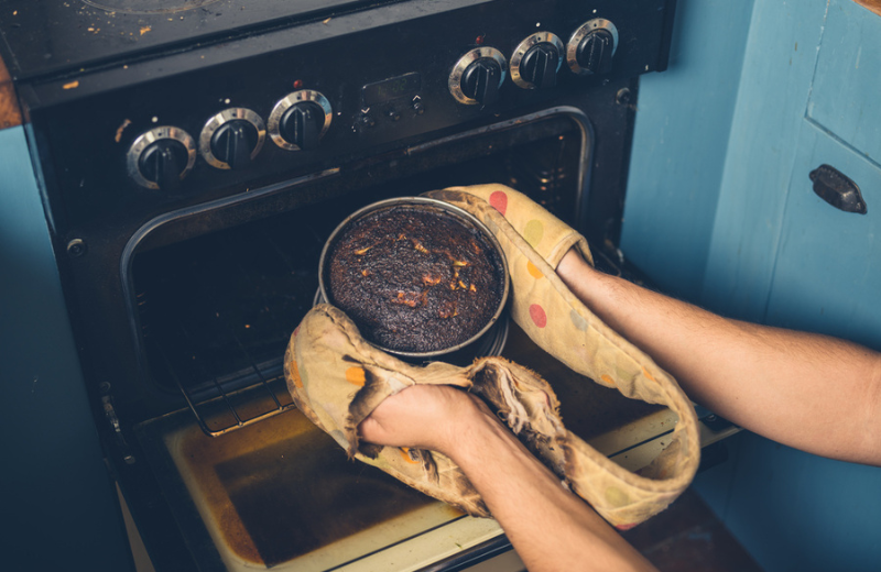 person removing burnt cake from oven