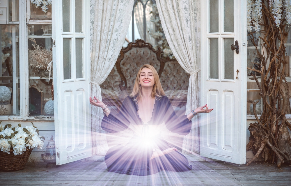 Woman meditating and smiling with bright light radiating from her stomach area