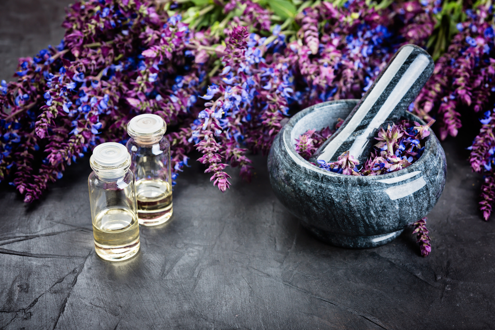 A bowl of clary sage and clary sage oil in two little bottles