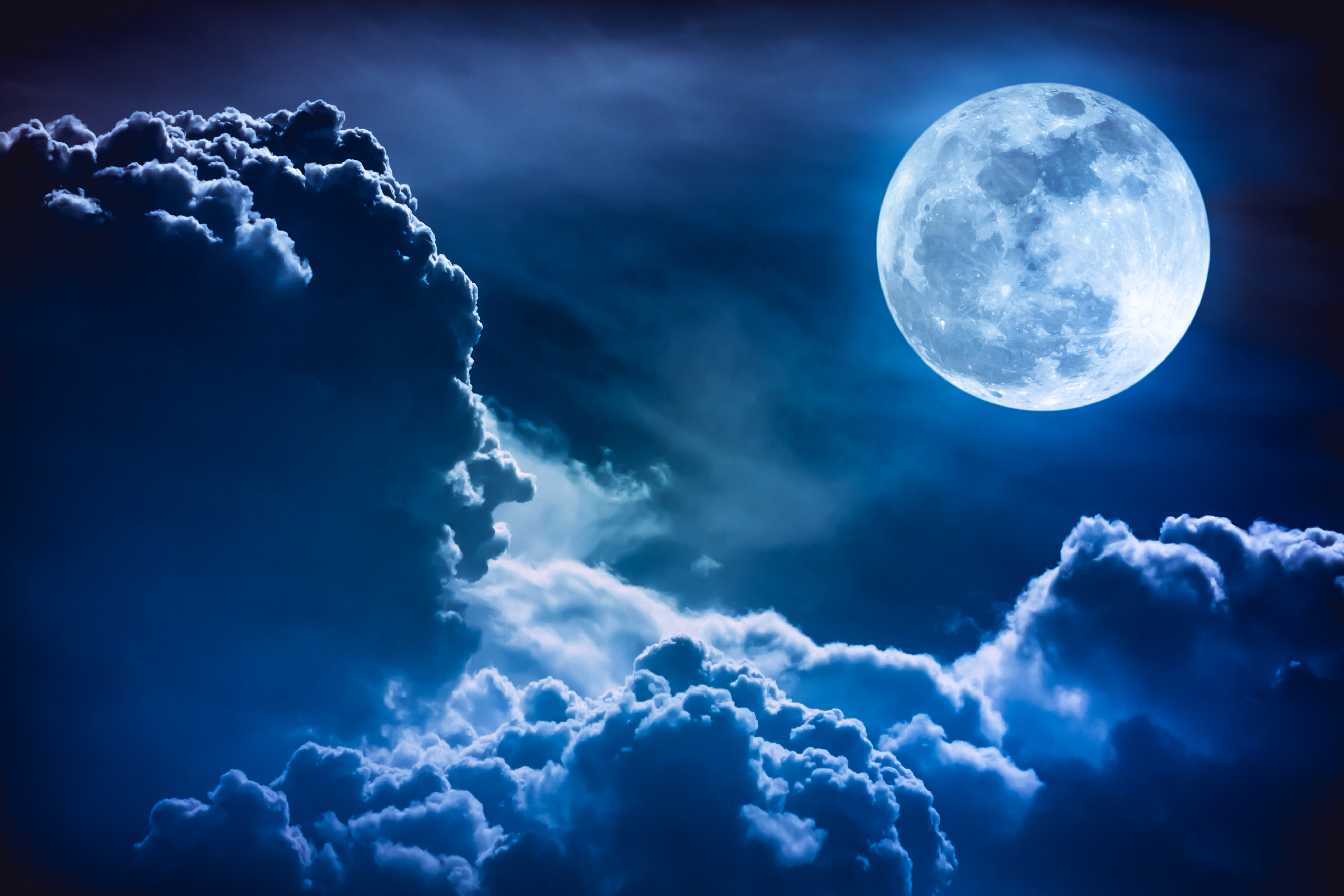 Image of a full moon in a night sky with clouds