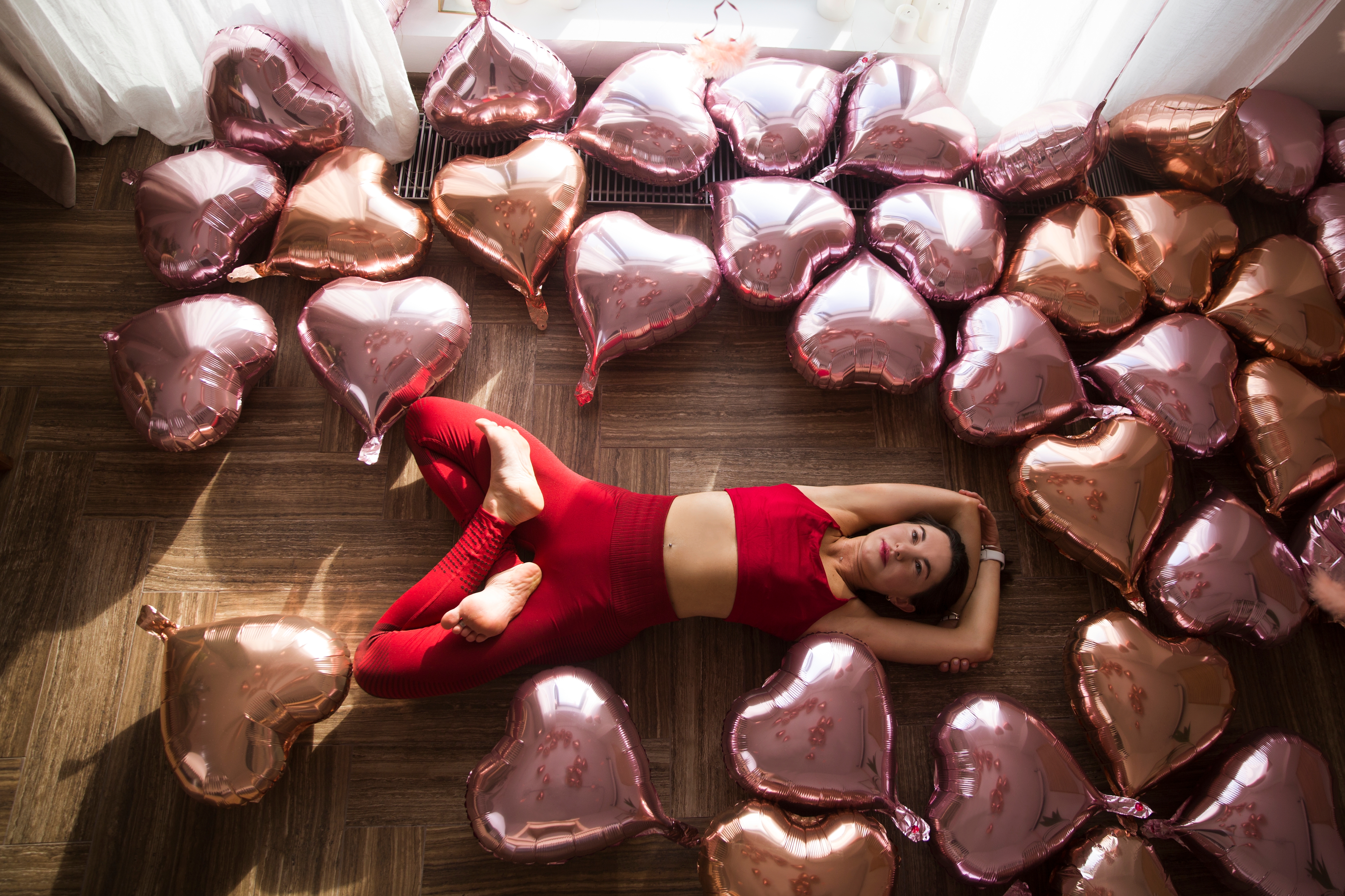 Someone lying on the floor surrounded by love heart balloons