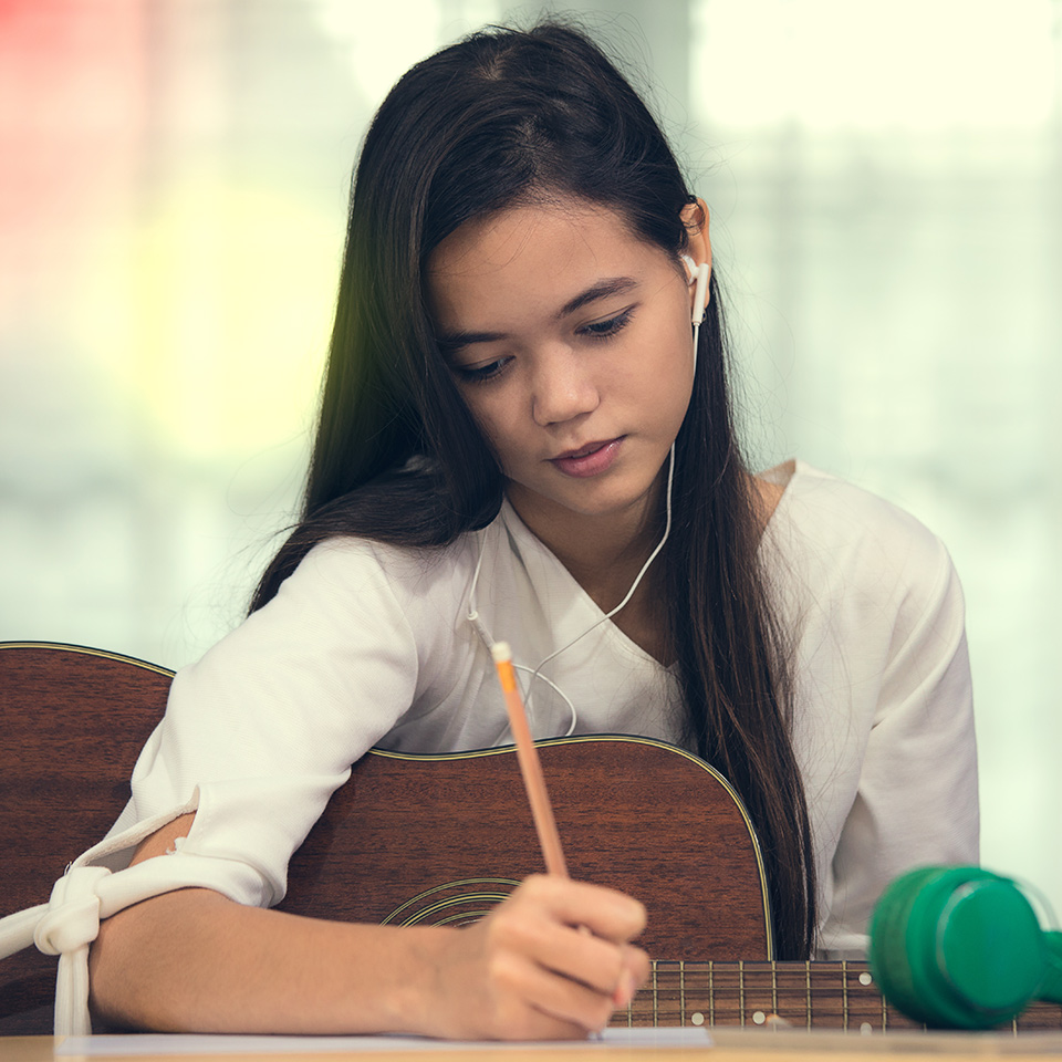 Woman with a guitar under her arm composing music