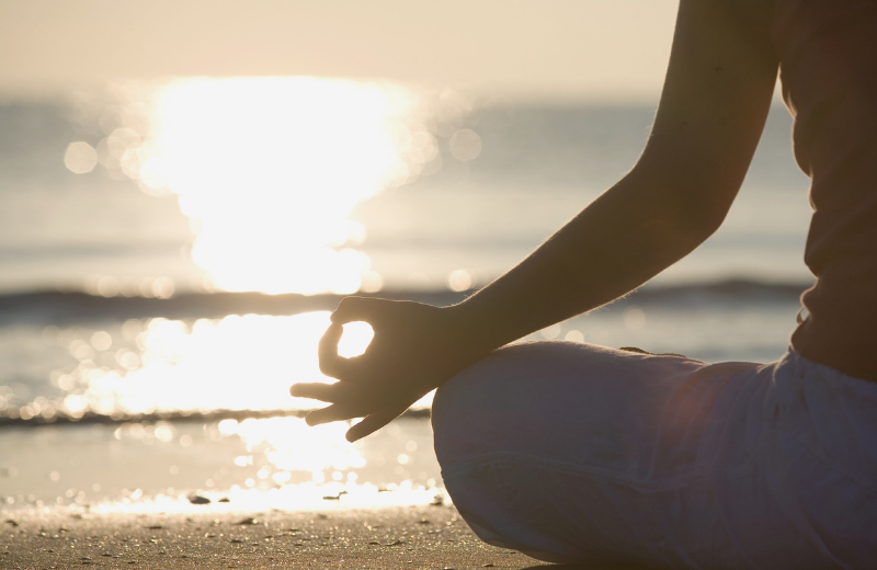 woman meditating on the beach