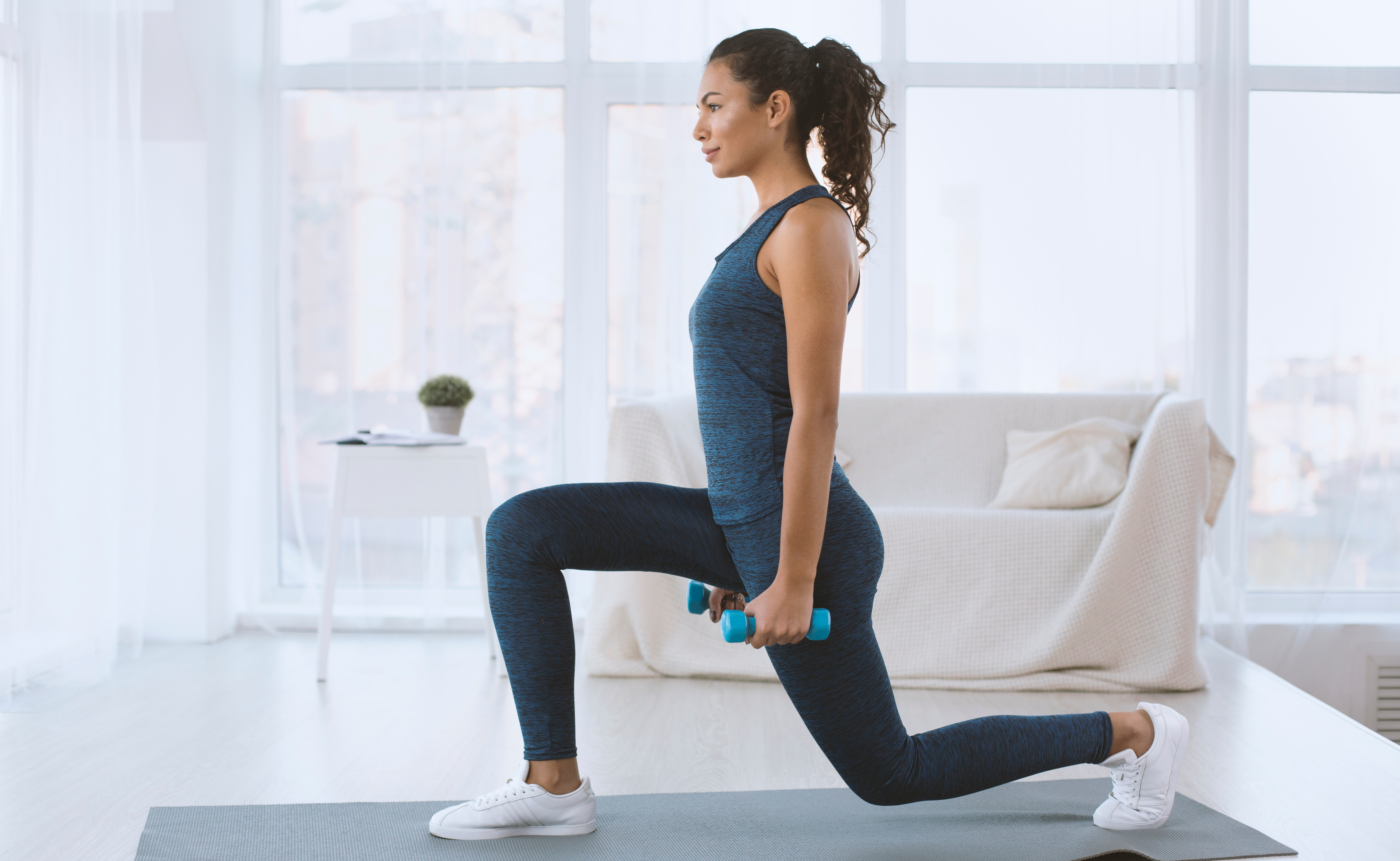 Woman doing lunges at home with weights