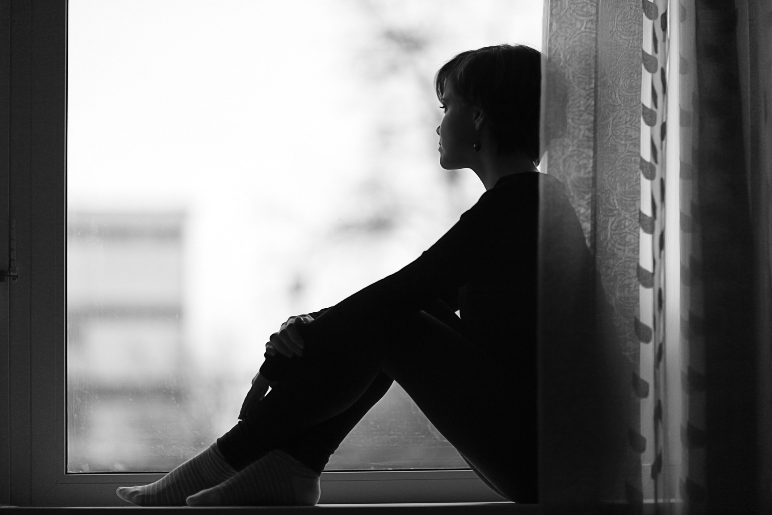 Sad and lonely woman looking out of the window