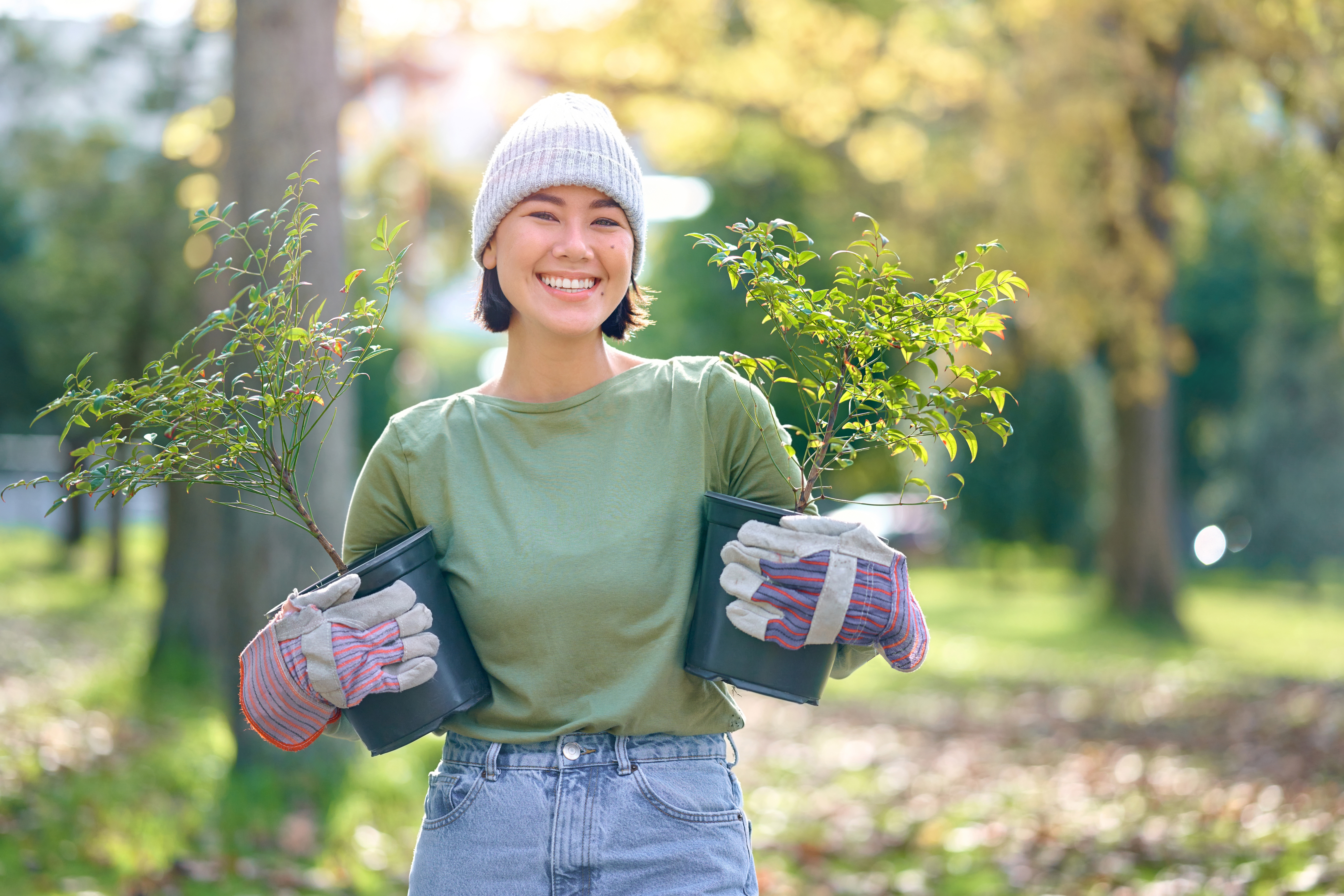 Happy woman holding plant pots outdoors gardening