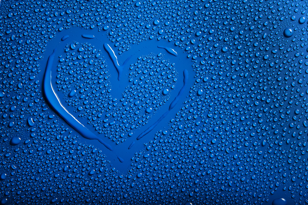 Blue background with lots of drops of condensation and water with a heart drawn on