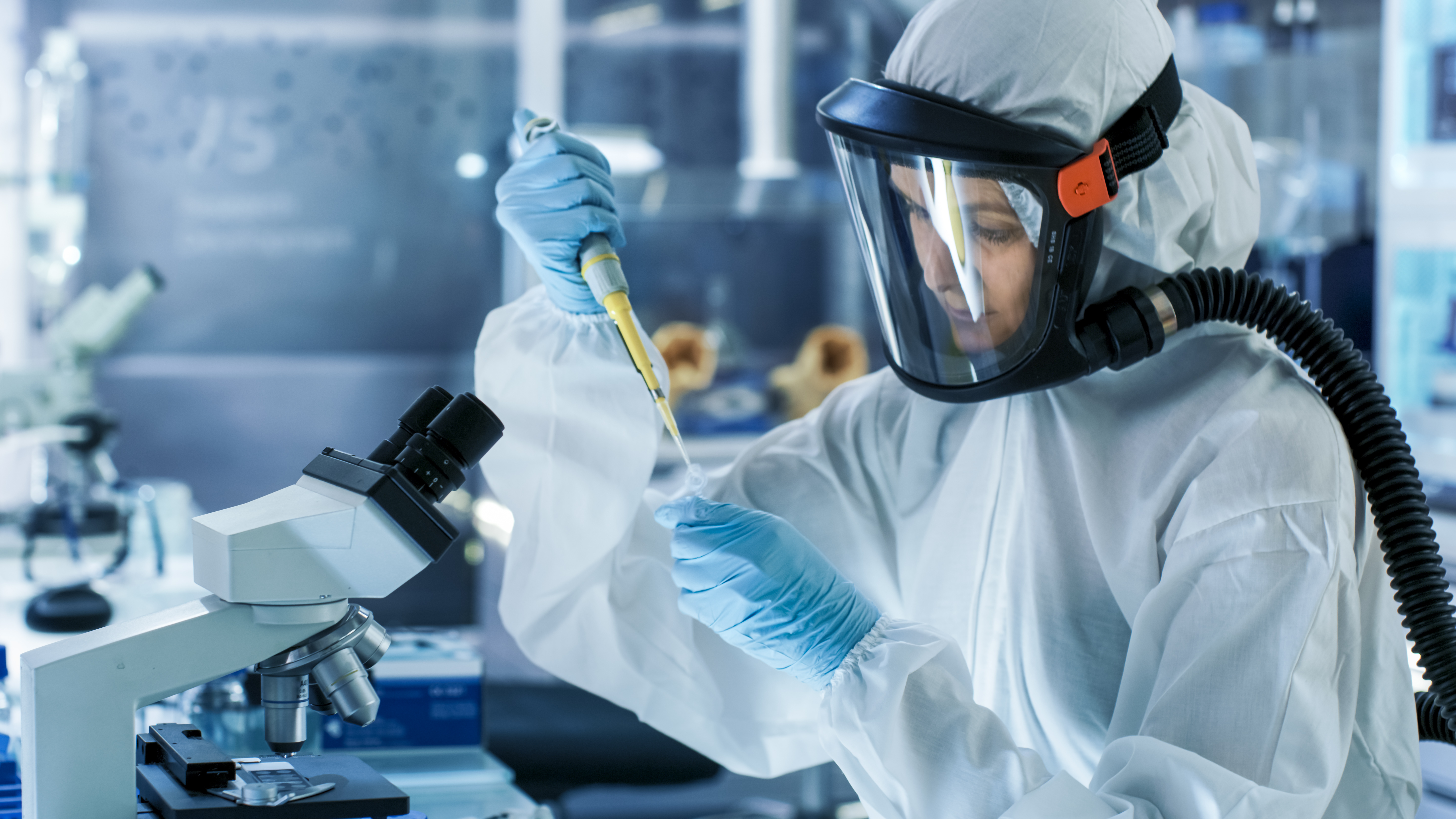 Someone in a protective suit and mask, experimenting with various liquids