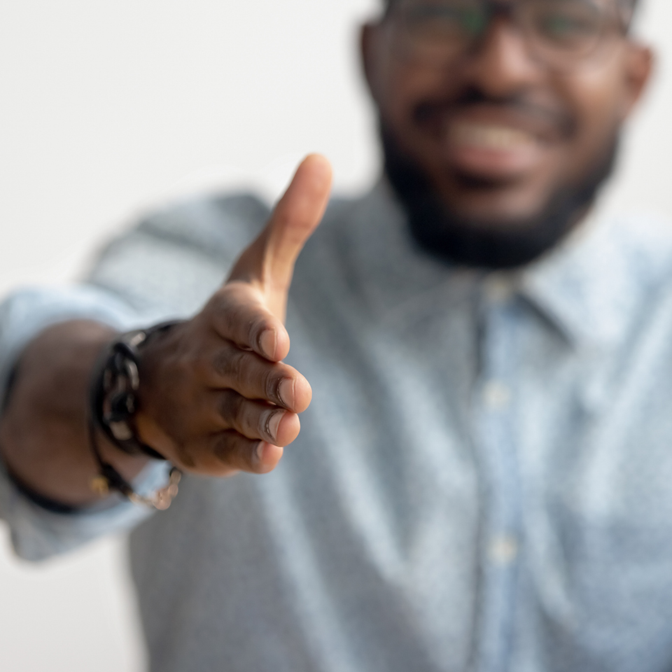 Interviewer extending hand at camera for a handshake