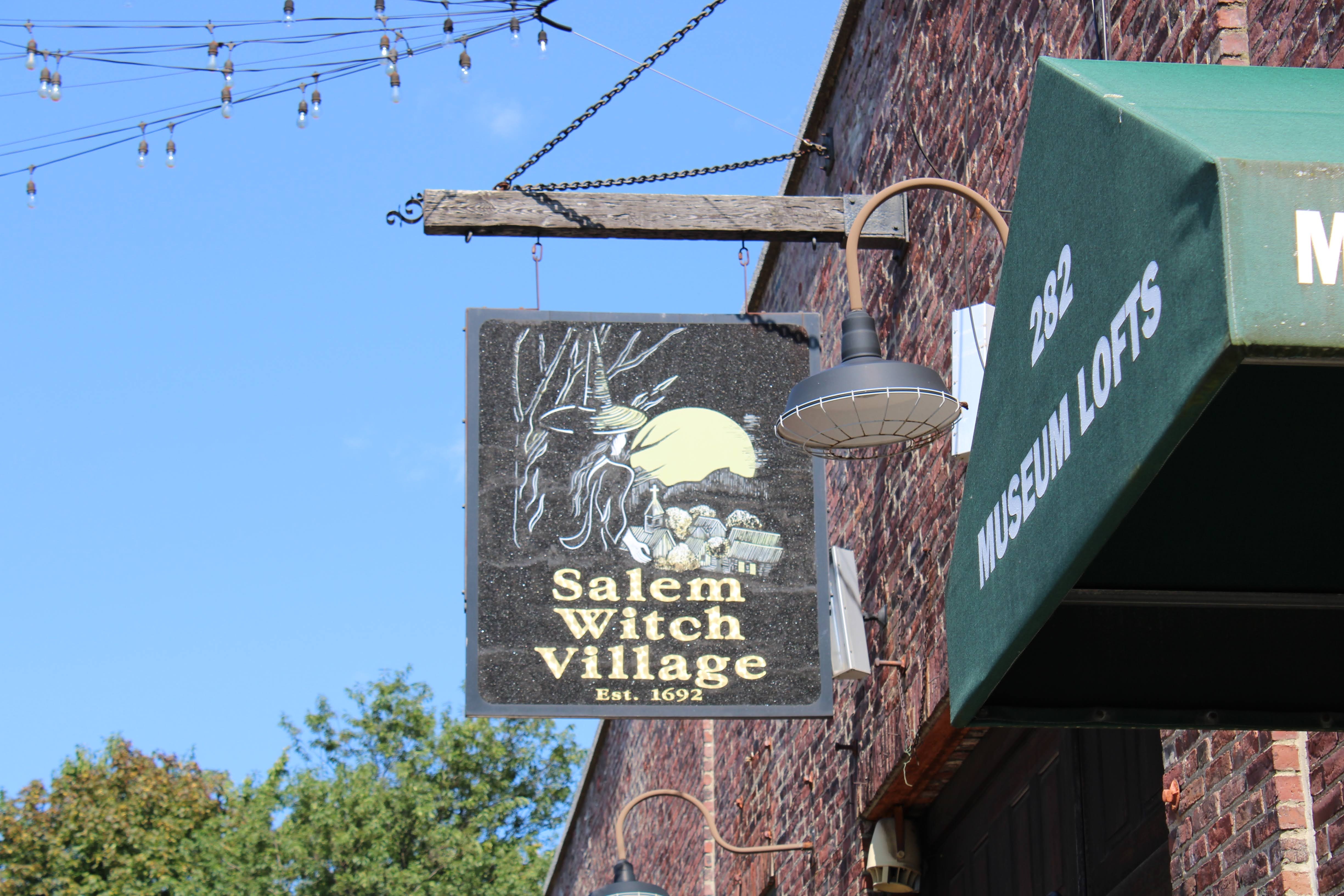 Salem witch village sign hanging from building
