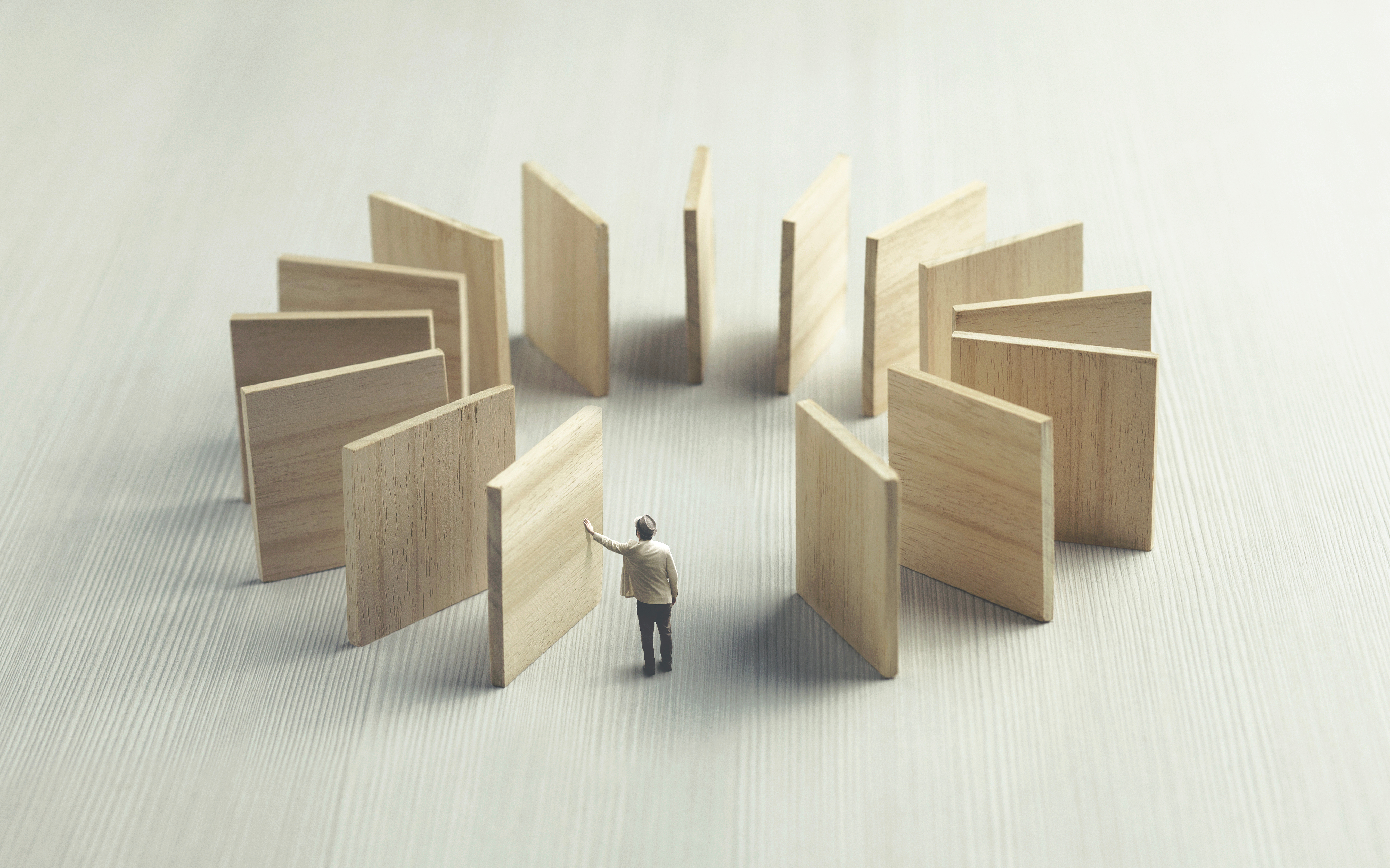 Figurine of a man pushing down a block representing the domino effect, when the final block falls it will come back to him