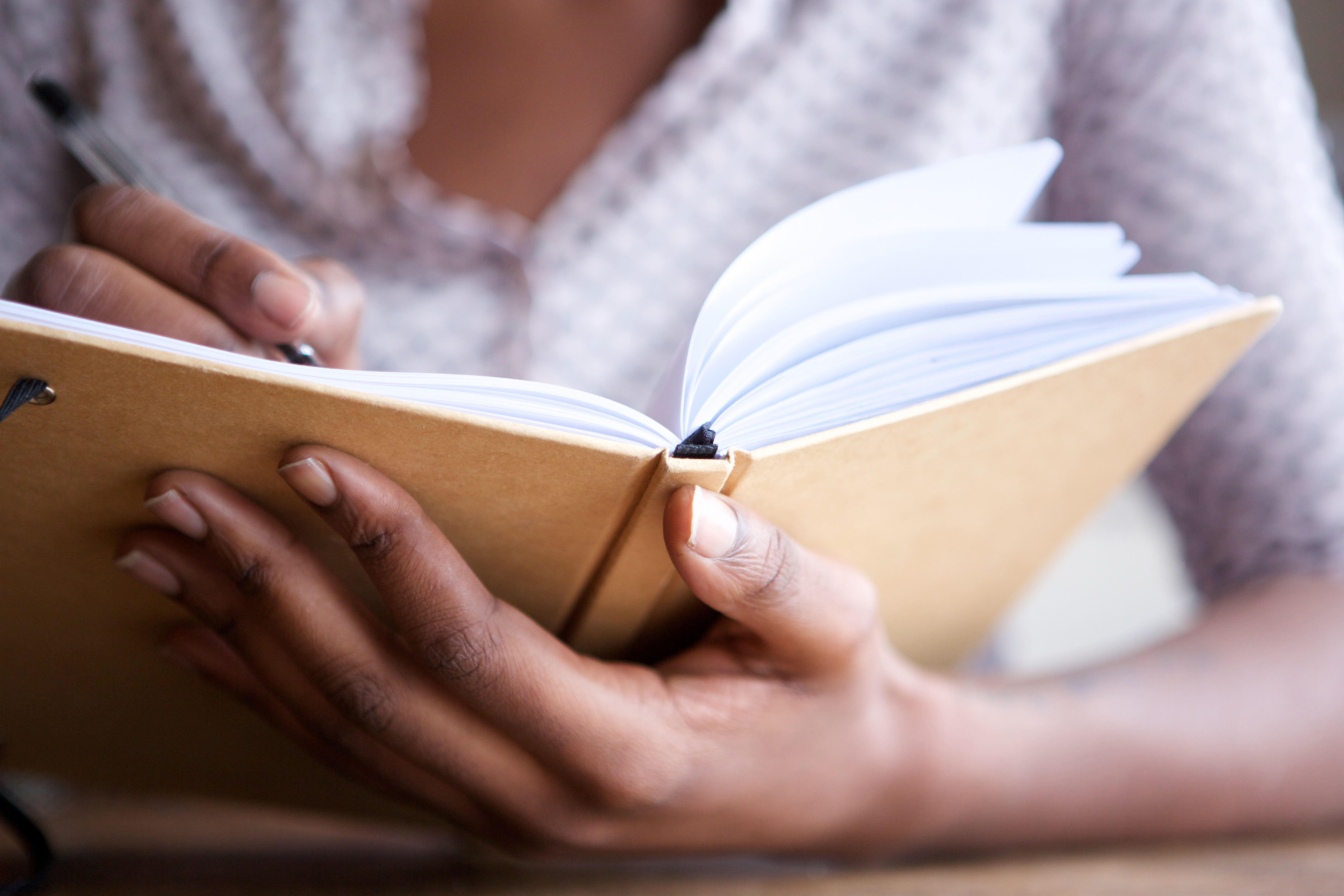 Woman writing in journal, up close image