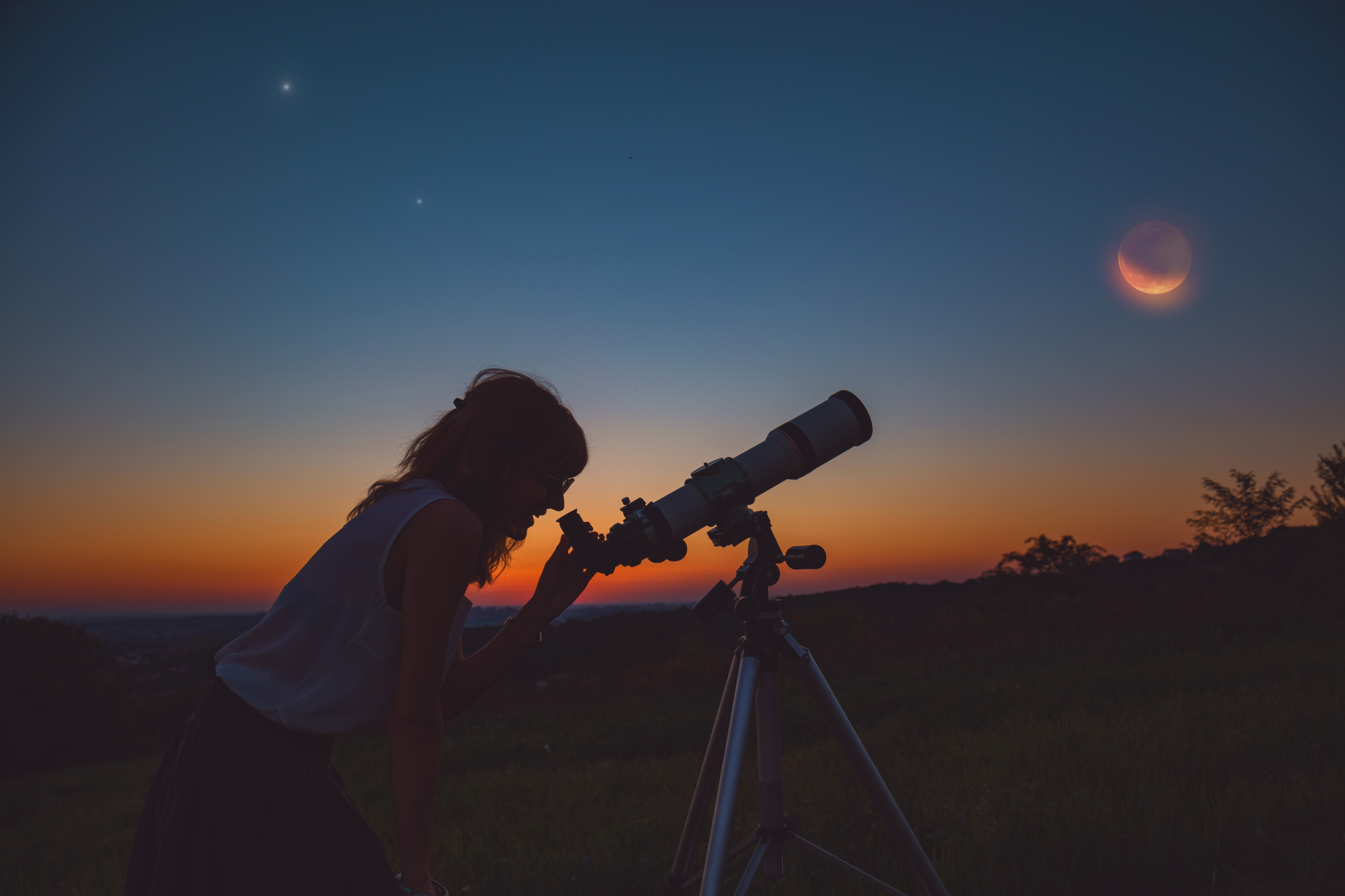 Girl viewing a lunar eclipse through a telescope