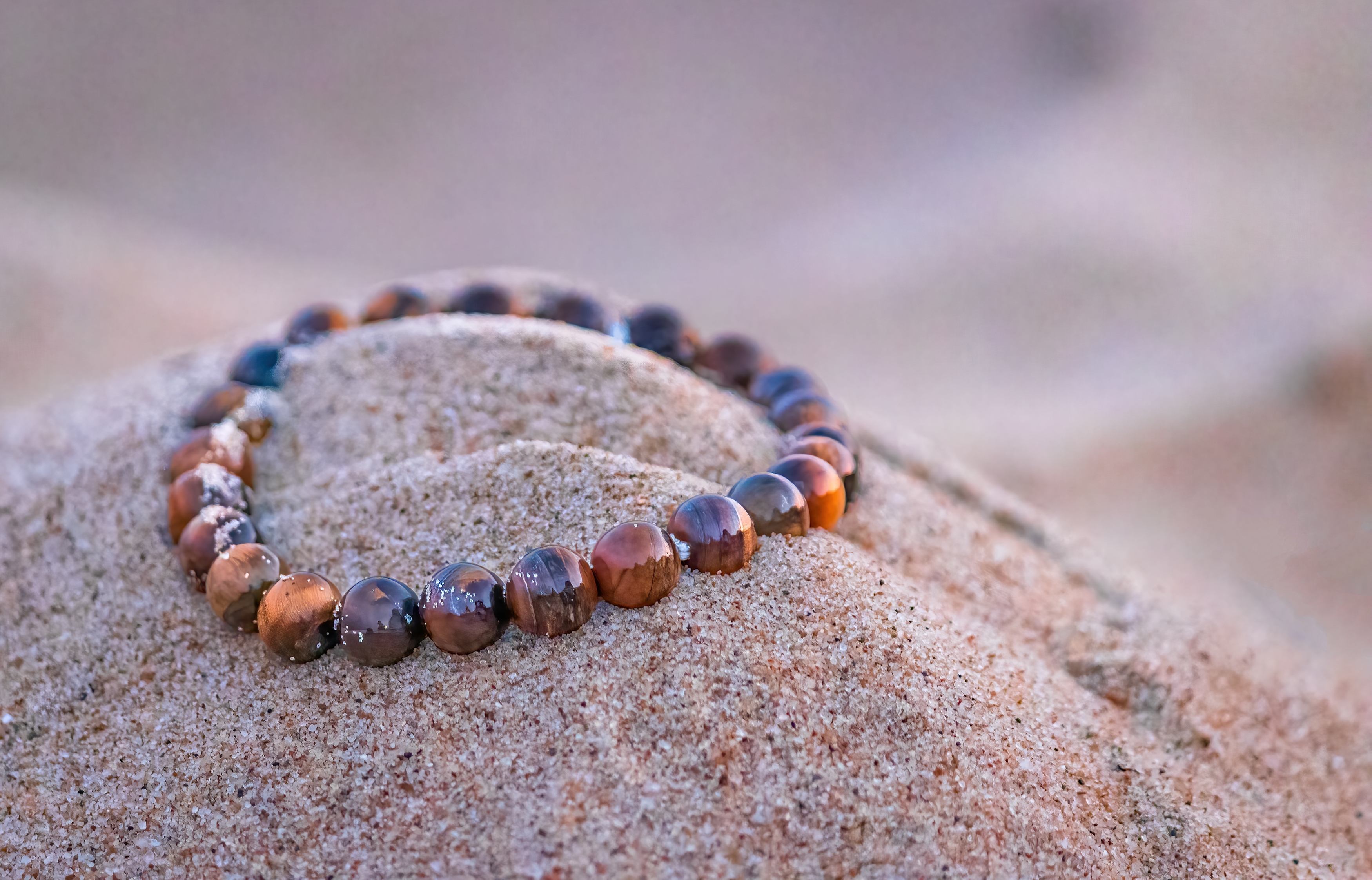 A Tiger's Eye bracelet on top of sand