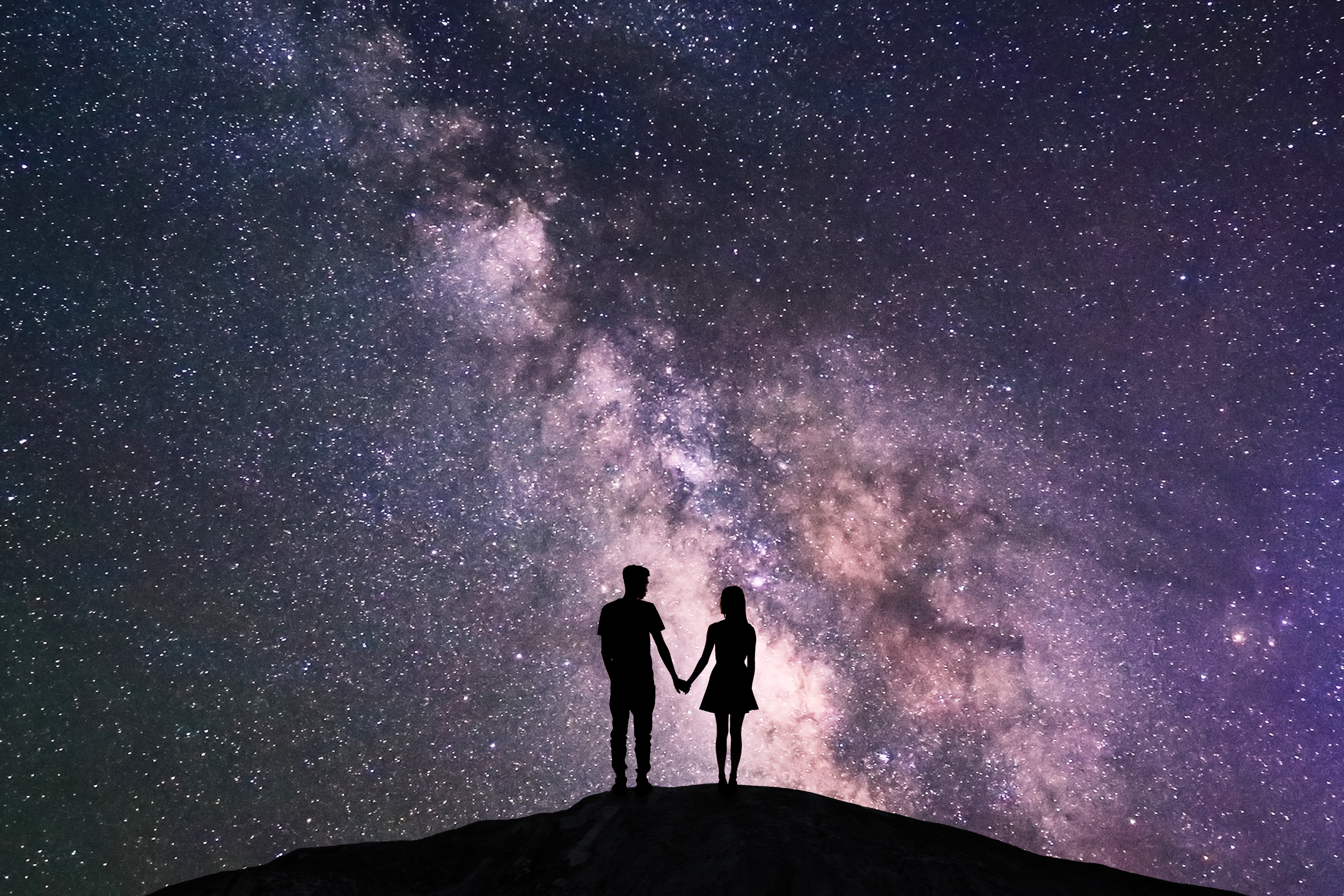 Silhouette of a couple holding hands in front of the night sky