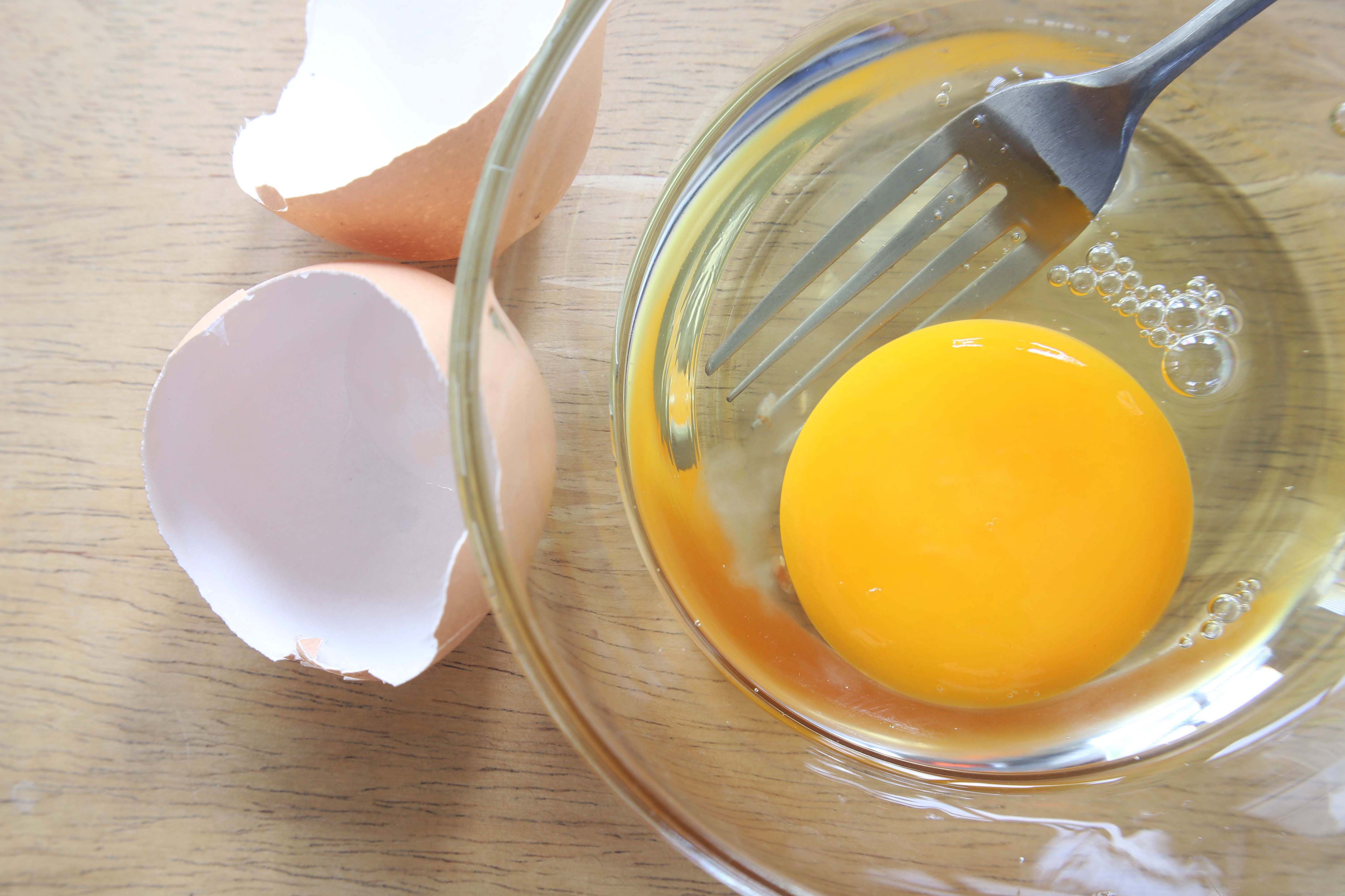 Raw egg in a bowl with egg shell