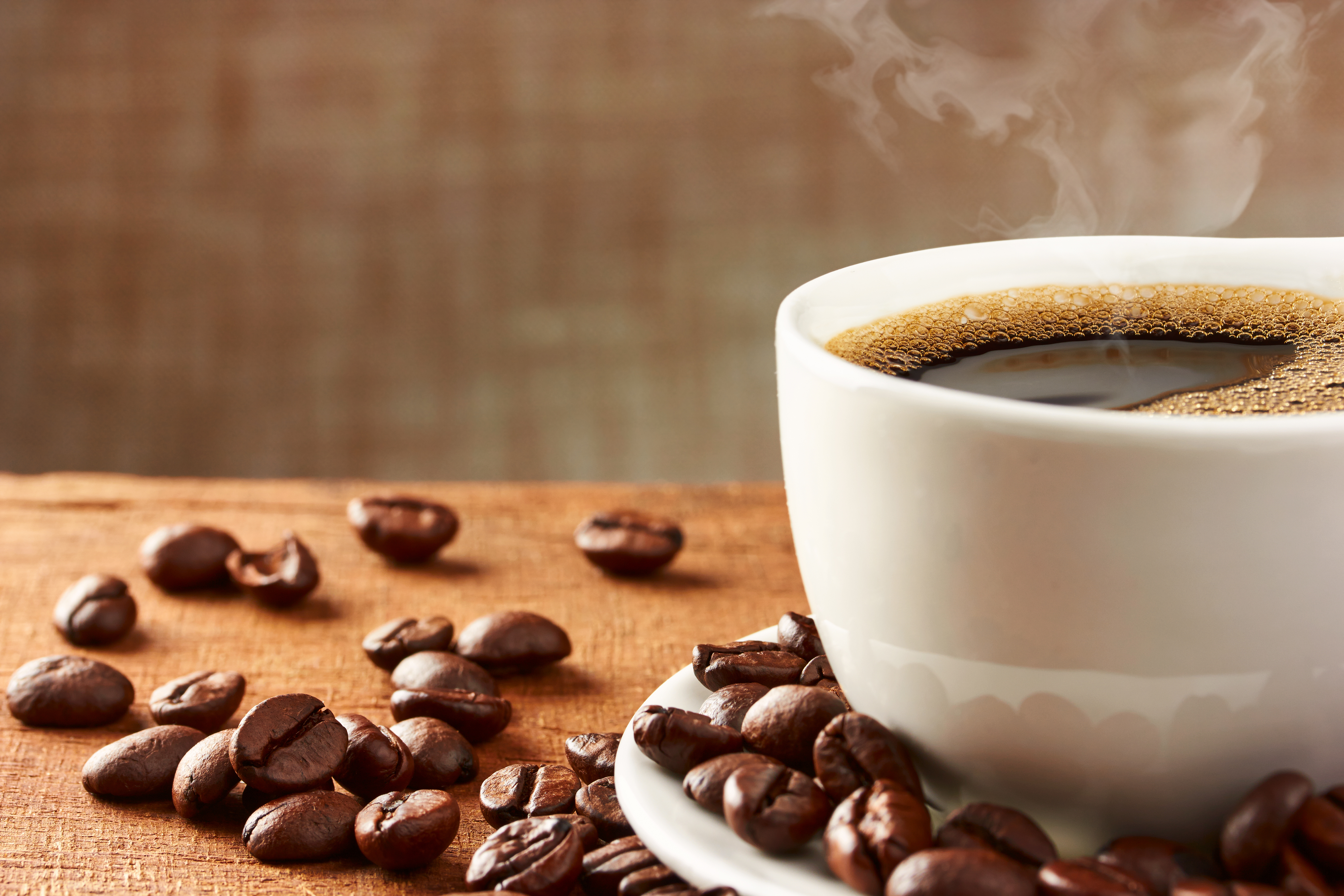 Hot coffee in a white mug with scattered coffee beans