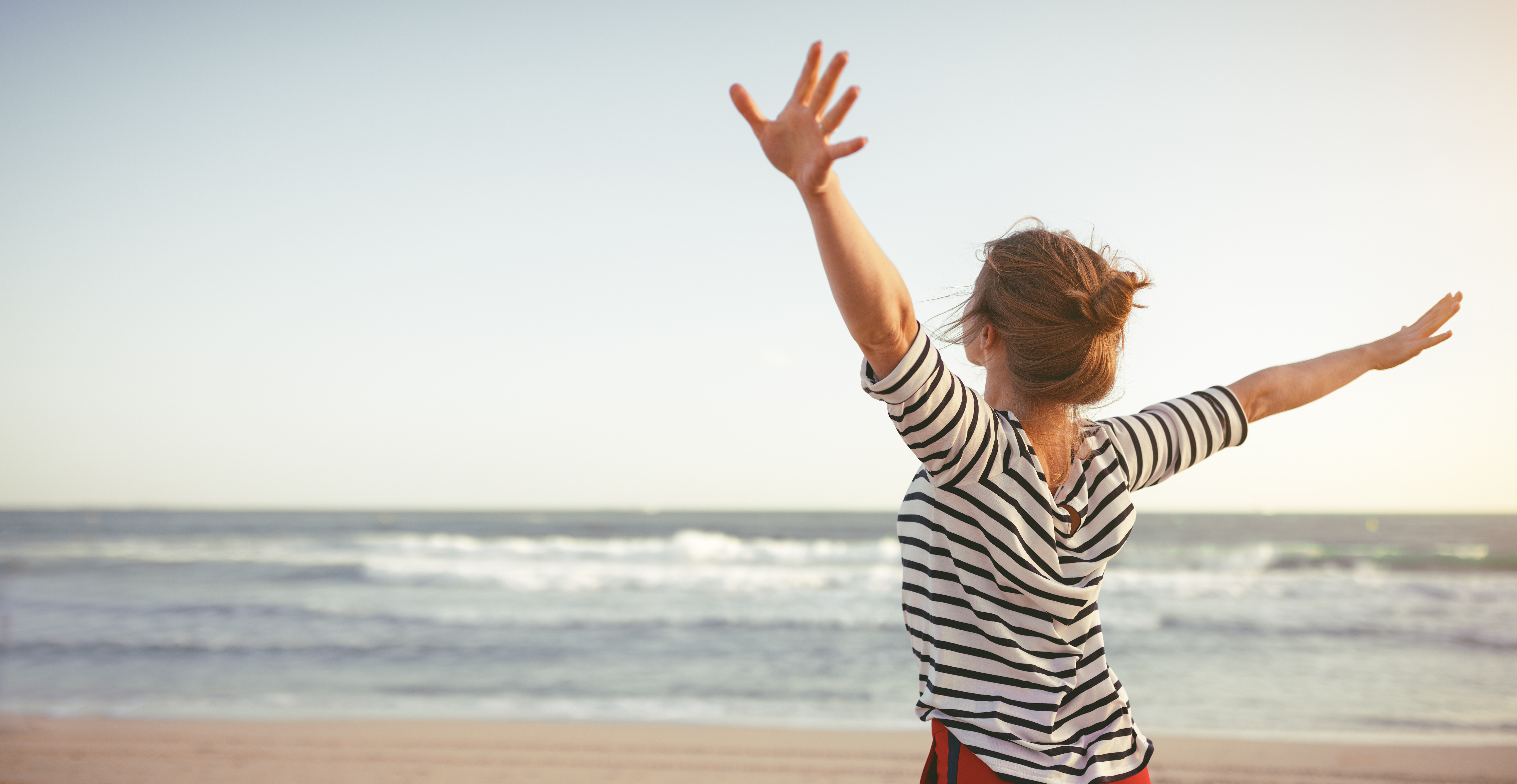 Freedom, a woman spreading her arms at the beach