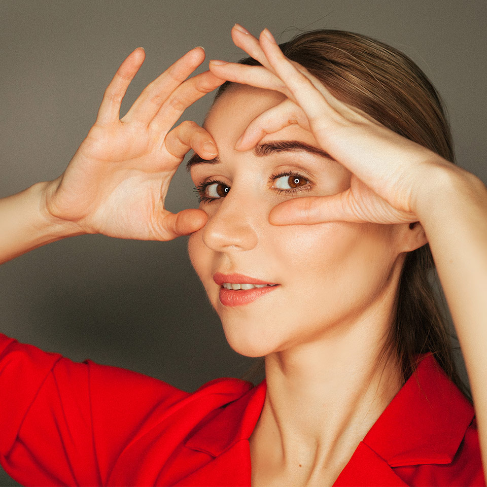 Woman looks at camera whilst doing face yoga
