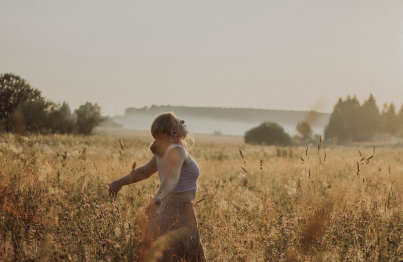 woman in wheat fiels with arms out