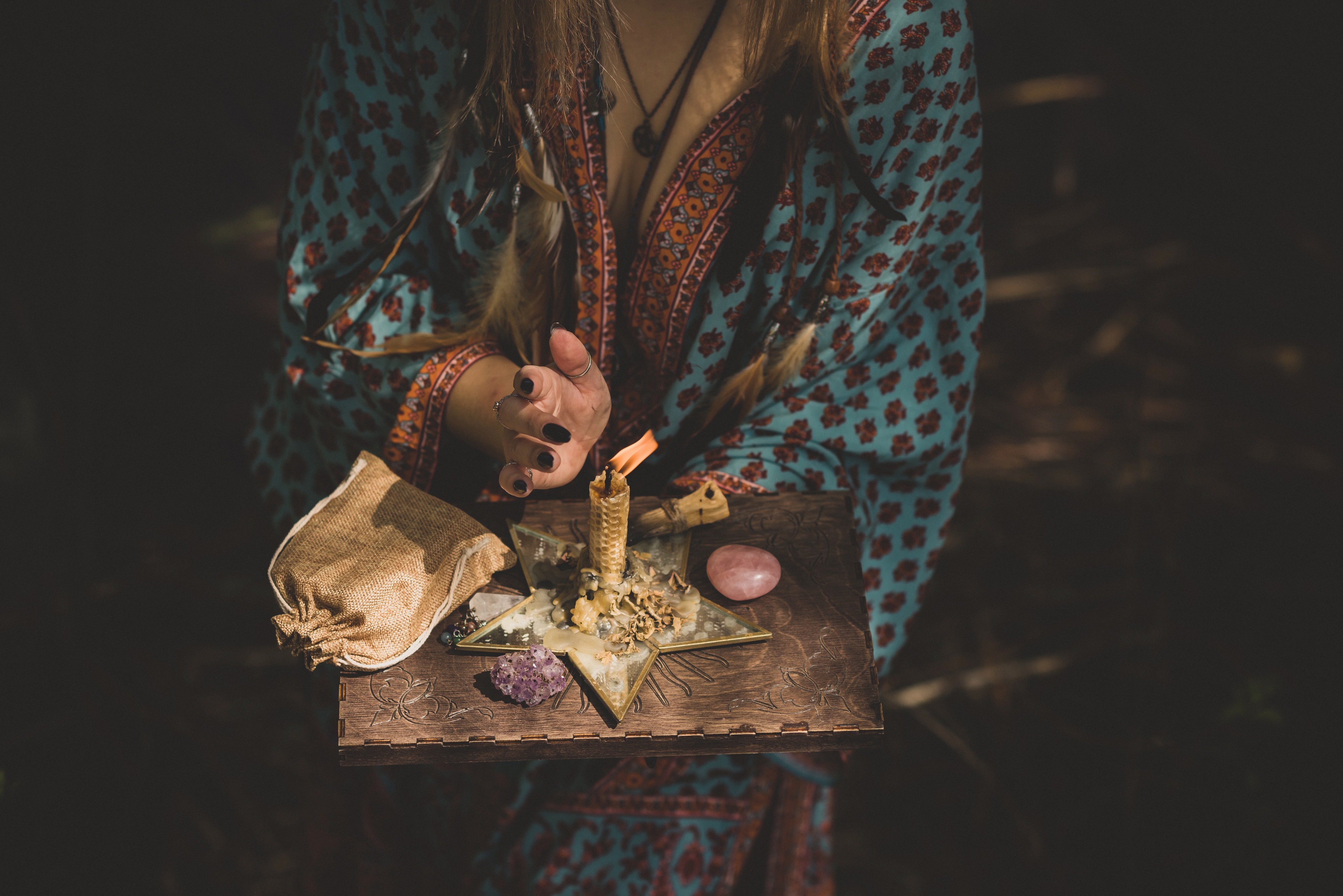 A spell being cast with a lit candle and various crystals surrounding the candle