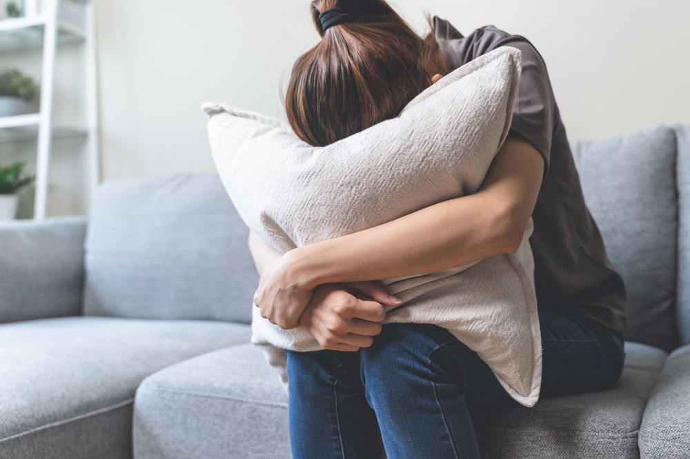 Woman sat on a sofa with her head in a pillow