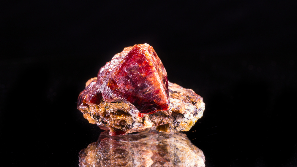 A raw piece of Red Zircon on a black background