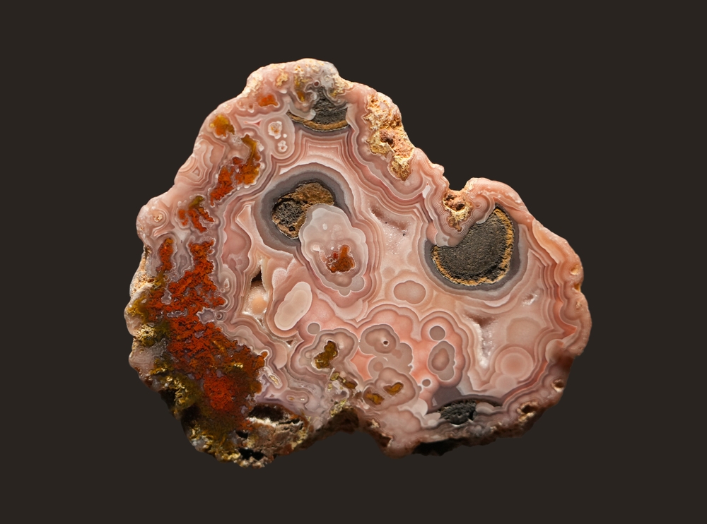 The inside of a piece of Pink Lace Agate on a black background