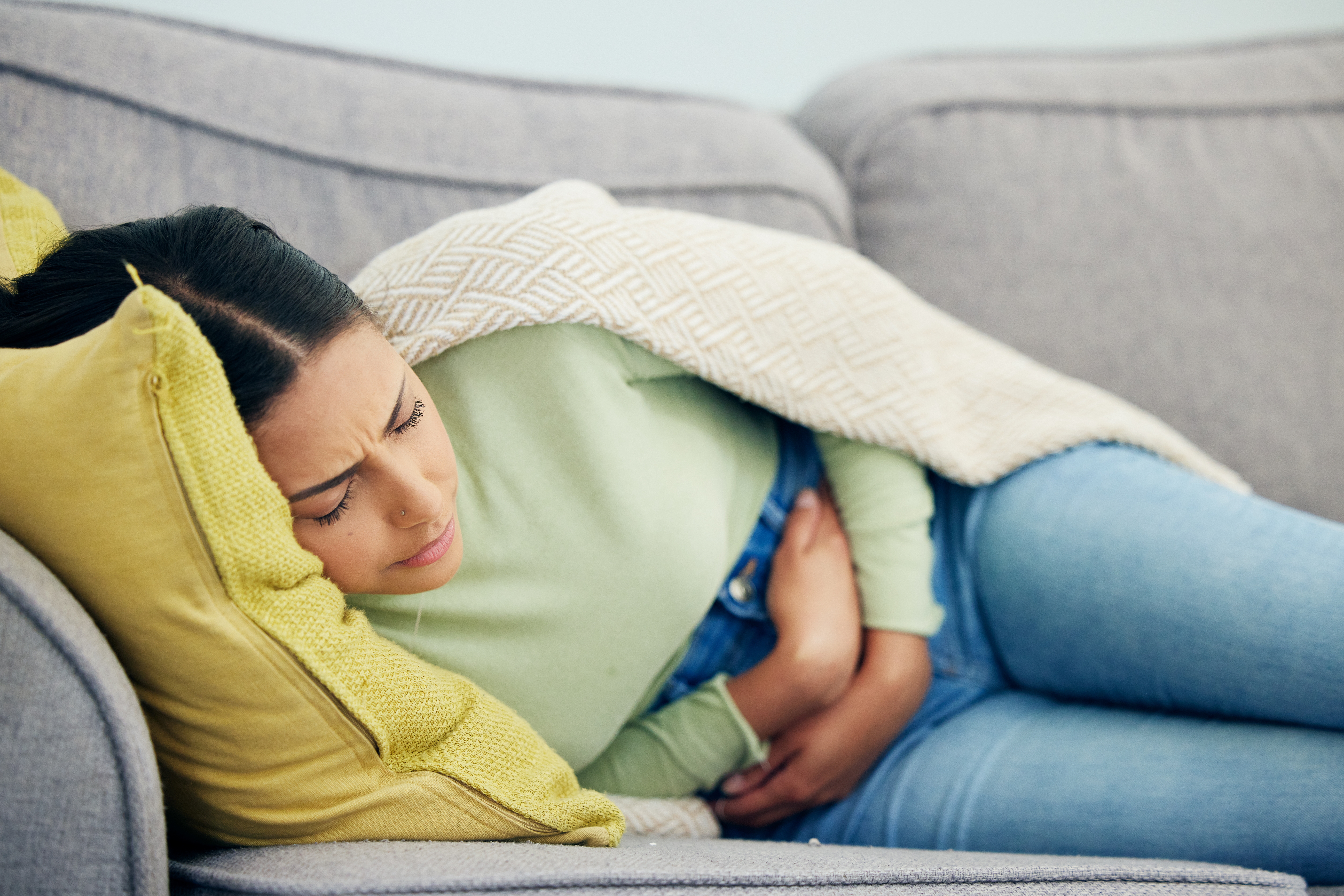 Woman lying on the couch with IBS pain