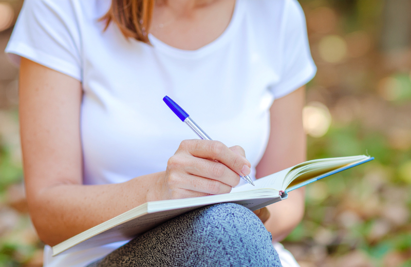 woman writing in notebook outside