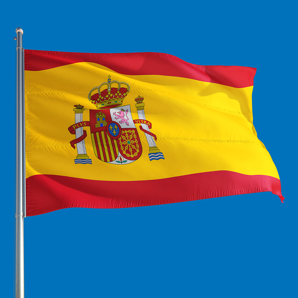 Spanish flag waving in the wind on a deep blue sky.