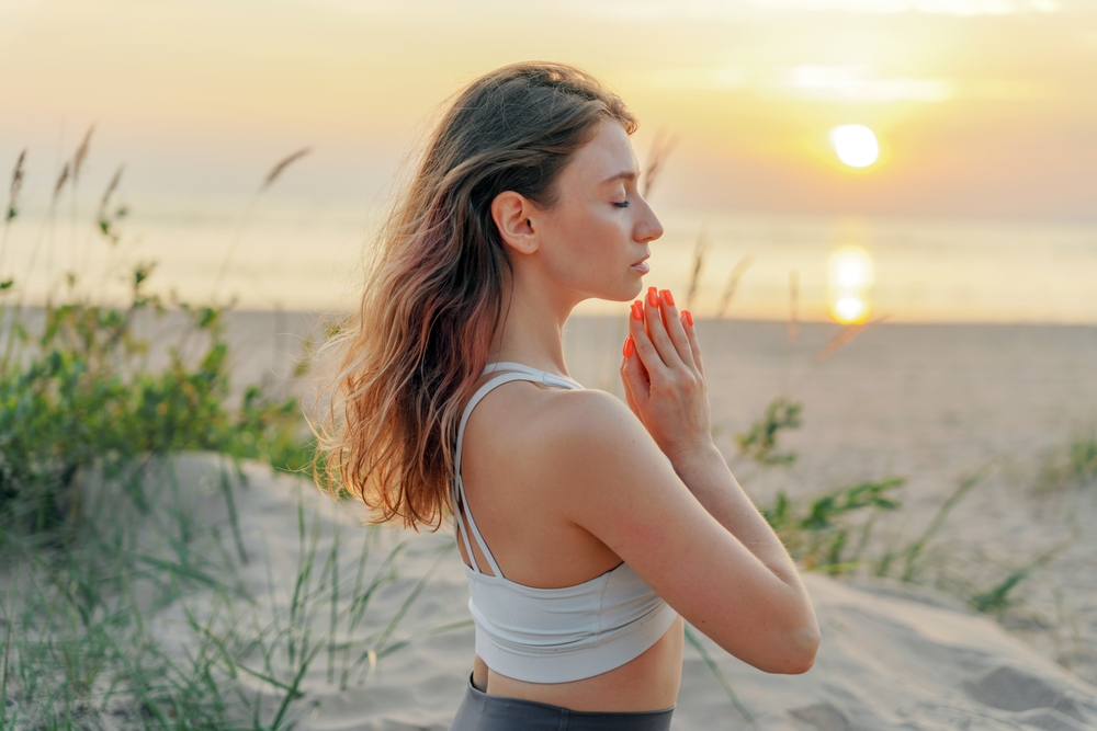 Woman outside meditating with her palms together and eyes closed