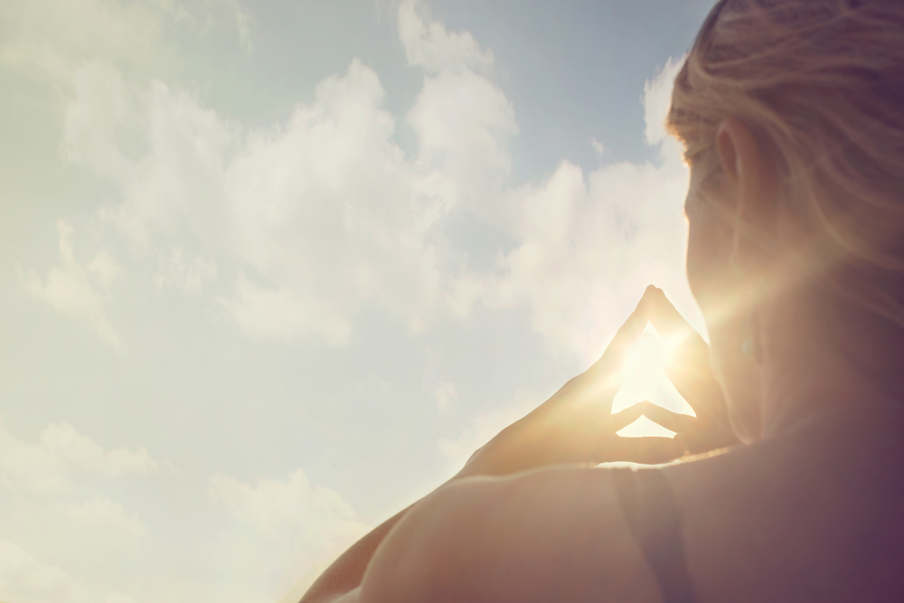 Woman with her fingertips together and the sun shining through her hands