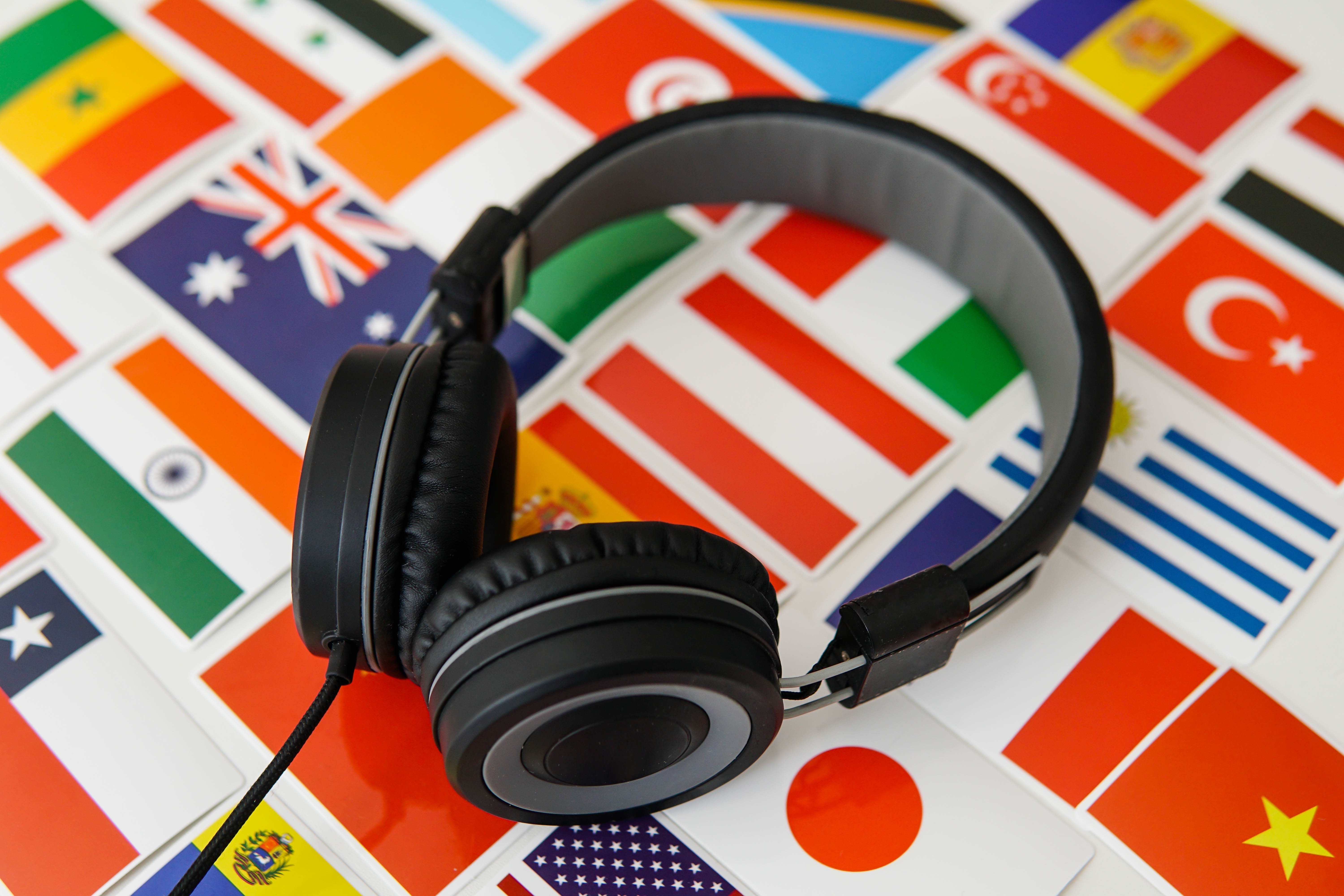 Learning a new language, headphones set against a backdrop of flags