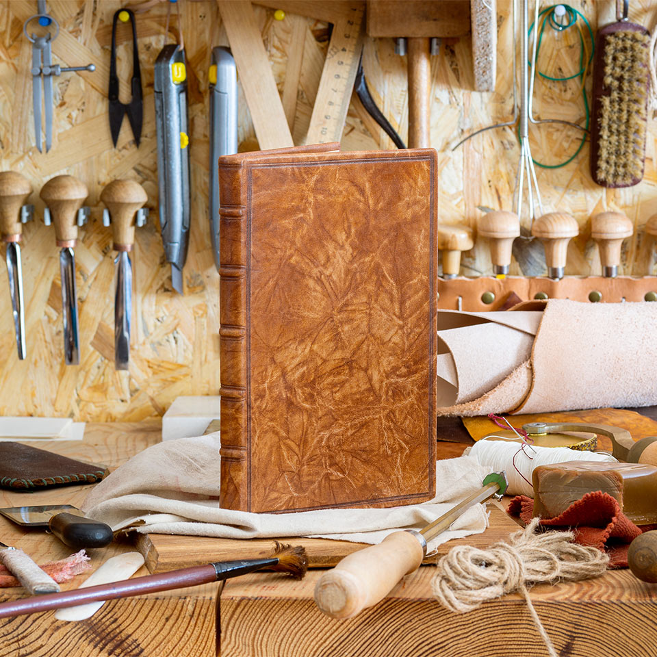 Hand bookbinding workshop and tools with a finished book on the workbench